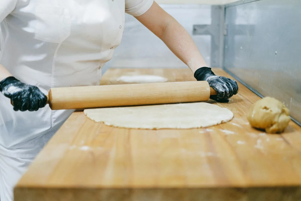 pâtissière qui étale de la pâte sur un plan de travail