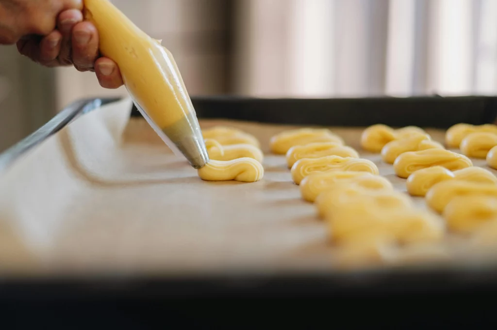 pâtissier qui poche de la pâte à choux